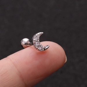 Macro shot of silver crescent moon piercing stud with tiny cubic zirconia on a fingertip
