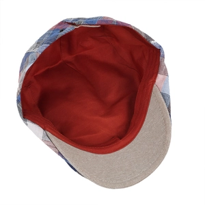 Detail view of plaid newsboy cap showing red lining and blue checkered fabric texture