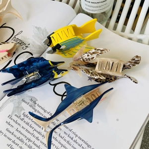 Marine life acetate hair claws featuring blue shark and sea turtle designs on a magazine