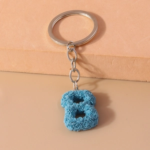 Detail of blue floral letter keychain with embossed rose texture and silver keyring