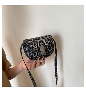 Detail of leopard print saddle bag featuring metal buckle and premium textured material