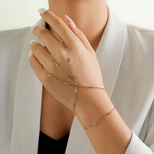 Detail of gold finger bracelet featuring delicate links and pearls on female model