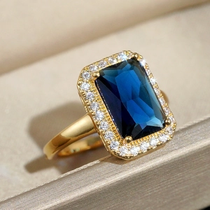 Macro shot of gold ring with rectangle blue gemstone and sparkling white crystal border