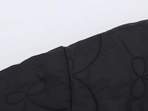 Gros plan sur le tissu matelassé noir avec des coutures à motif floral de la veste