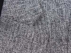 Macro view showing the high-density tweed fabric texture and woven herringbone pattern details