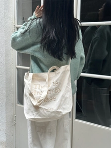Detail of canvas tote bag with embroidered letters and dual handle shoulder straps