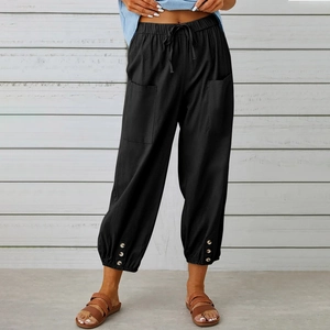 Dettaglio dei pantaloni neri in cotone e lino con coulisse e bottoni sul fondo gamba
