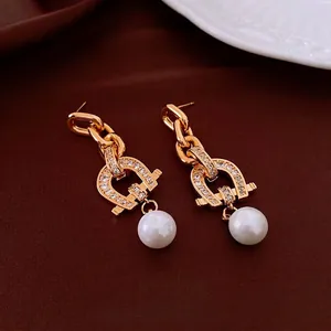 Golden horseshoe drop earrings with white pearls and sparkling zircons on silk