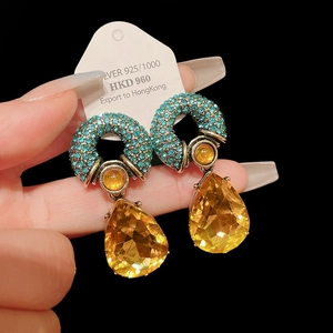 Macro shot of luxury vintage teardrop earrings with blue pavé crystals and yellow gems
