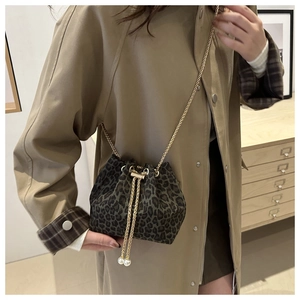 Leopard print suede bucket bag with gold chain strap and pearl accents on a model