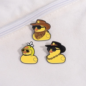 Trois pin's canard jaune en émail avec lunettes de soleil et chapeaux sur toile blanche