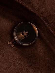 Close-up of a brown tortoiseshell button on high-quality suede jacket fabric