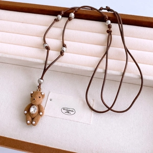 Detail of plush brown bear pendant with teardrop rhinestone on braided cord necklace