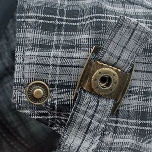 Détail de la boucle en bronze vintage et du tissu à carreaux gris sur un béret