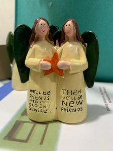 Detail of angel resin figurine holding an orange star with friendship engraving text