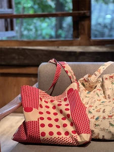 Détail de sacs fourre-tout en toile à pois rouges et motifs chiens sur un canapé