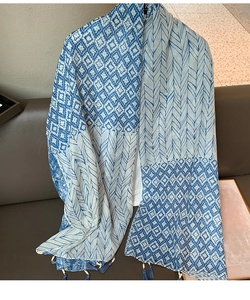 Detail of blue feather pattern scarf featuring decorative tassels and small beads at the edge