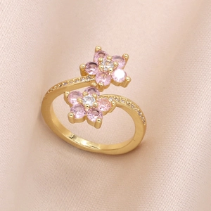 Gold open ring with colorful zircon flower petals on soft pink satin background