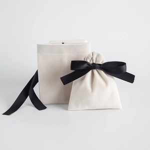 Detail of cream velvet jewelry pouch with elegant black drawstring and envelope ribbon