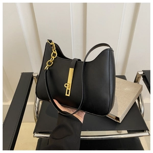 Detail of hobo bag with thick gold chain strap and vertical metal buckle clasp