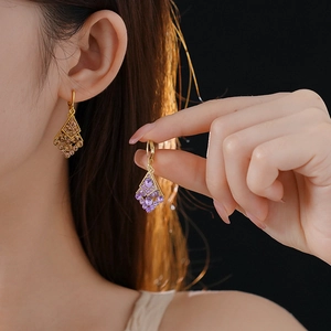 Close-up of diamond-encrusted rhombic leaf earrings in gold-brown and silver-purple finishes