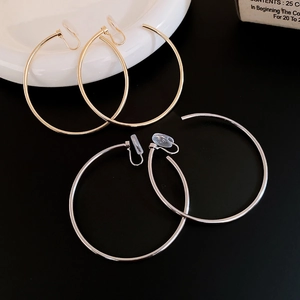Polished gold and silver hoop ear clips with silicone pads on a ceramic plate