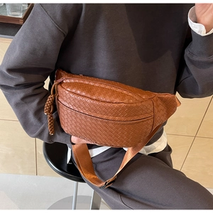 Close-up of brown woven texture chest bag with adjustable strap and decorative zipper pull