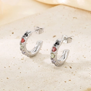 Détail de boucles d'oreilles argentées en C avec pierres colorées sur plaque en pierre beige