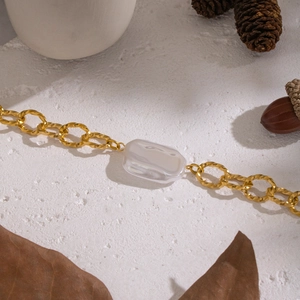 Dettaglio del bracciale a catena dorata con rettangolo in resina bianca su pietra