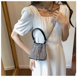 Detail of a sparkling black bucket bag with silver rhinestones and a chain strap