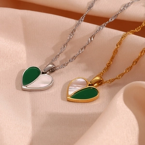 Detail of heart pendant with green and shell textures on soft pink velvet background