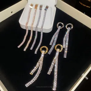 Elegant silver and gold tassel earrings with round cubic zirconia on a black velvet tray