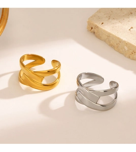 Detail view of gold and silver layered crisscross rings on a textured stone surface