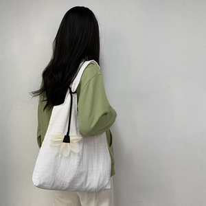 Detail of white textured canvas tote bag featuring a large 3D floral charm on the side