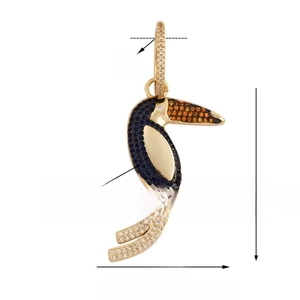 Macro detail of gold-plated toucan pendant with blue zircon stones and orange beak