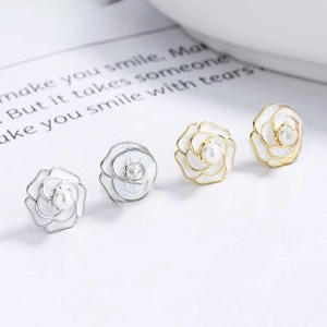 Macro shot of two pairs of 925 silver camellia pearl earrings in gold and silver finish
