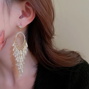 Close-up of elegant long gold tassel earrings with crystals on a female model