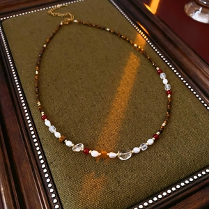 Detail of beaded necklace with tiger eye, pearls and golden chain on vintage wooden frame