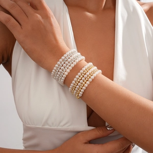 Detail of multilayer pearl and rhinestone stacked bracelets on a woman's wrist