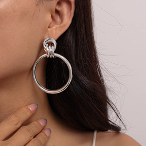 Close-up of geometric silver hoop earrings worn by a model with a metallic finish