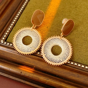 Detail view of gold hoop earrings with brown enamel and white cotton thread wrapping