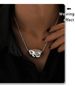 Wearing effect of a silver geometric liquid metal pendant necklace on a black shirt
