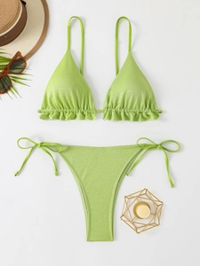 Mise à plat d'un bikini scintillant vert citron à volants avec accessoires de plage chic