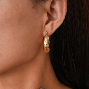 Close-up of elegant gold drop hoop earrings with polished mirror finish on model