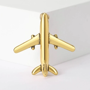 Detailed view of a vintage golden airplane brooch pin on a clean minimalist background