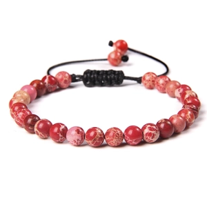 Detalle macro de cuentas de piedra natural roja de 6 mm en pulsera tejida a mano ajustable