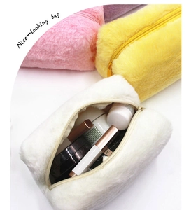 Dettaglio ravvicinato della borsa trucco in peluche bianca con morbida trama e zip beige