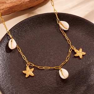 Détail des pendentifs étoiles de mer dorées et coquillages cauris blancs sur un collier d'été