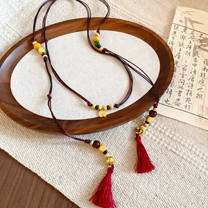 Detail of Chinese style waist chain with colorful beads and red silk tassels on wooden tray