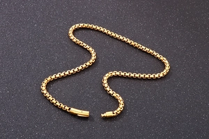 Detail of a golden stainless steel box chain necklace with secure clasp on black background